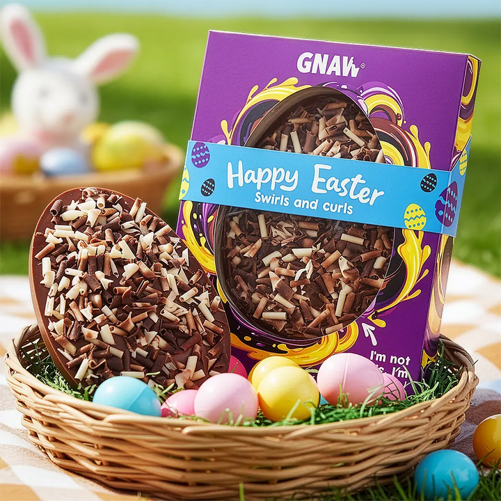 Easter basket with chocolate eggs and a package of GNAW Swirls and Curls easter egg on a grassy background.